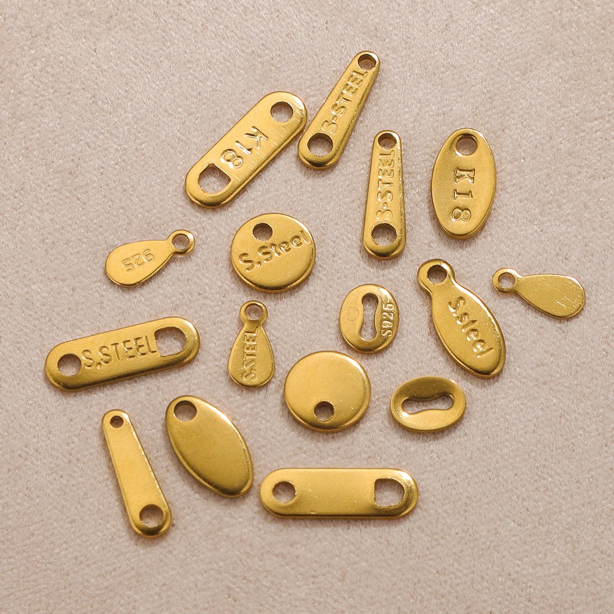 Actual gold-tone stainless steel tag samples in round, oval and bar shapes
