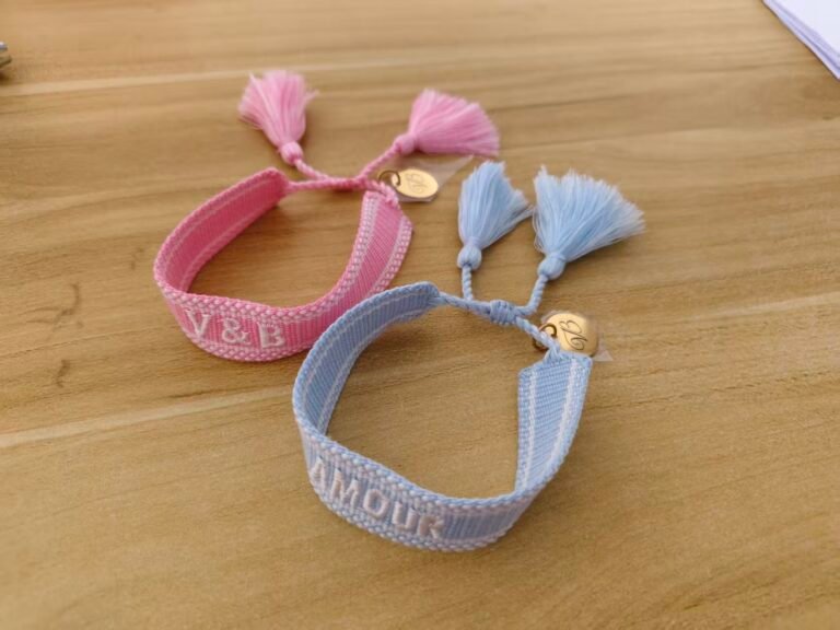 Actual pastel blue and pink customer woven bracelets with tassels and round logo tags