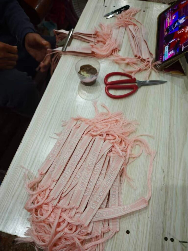 Actual hand assembly of pink woven message bracelets and their cord ties